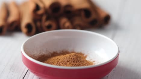 cinnamon powder in a bowl with cinnamon sticks