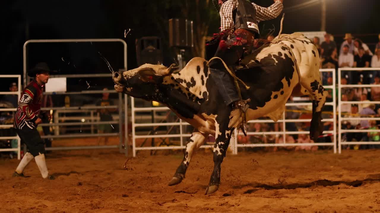 A thrilling bull riding sequence unfolds at night, showcasing the rider's skill and the bull's power.
