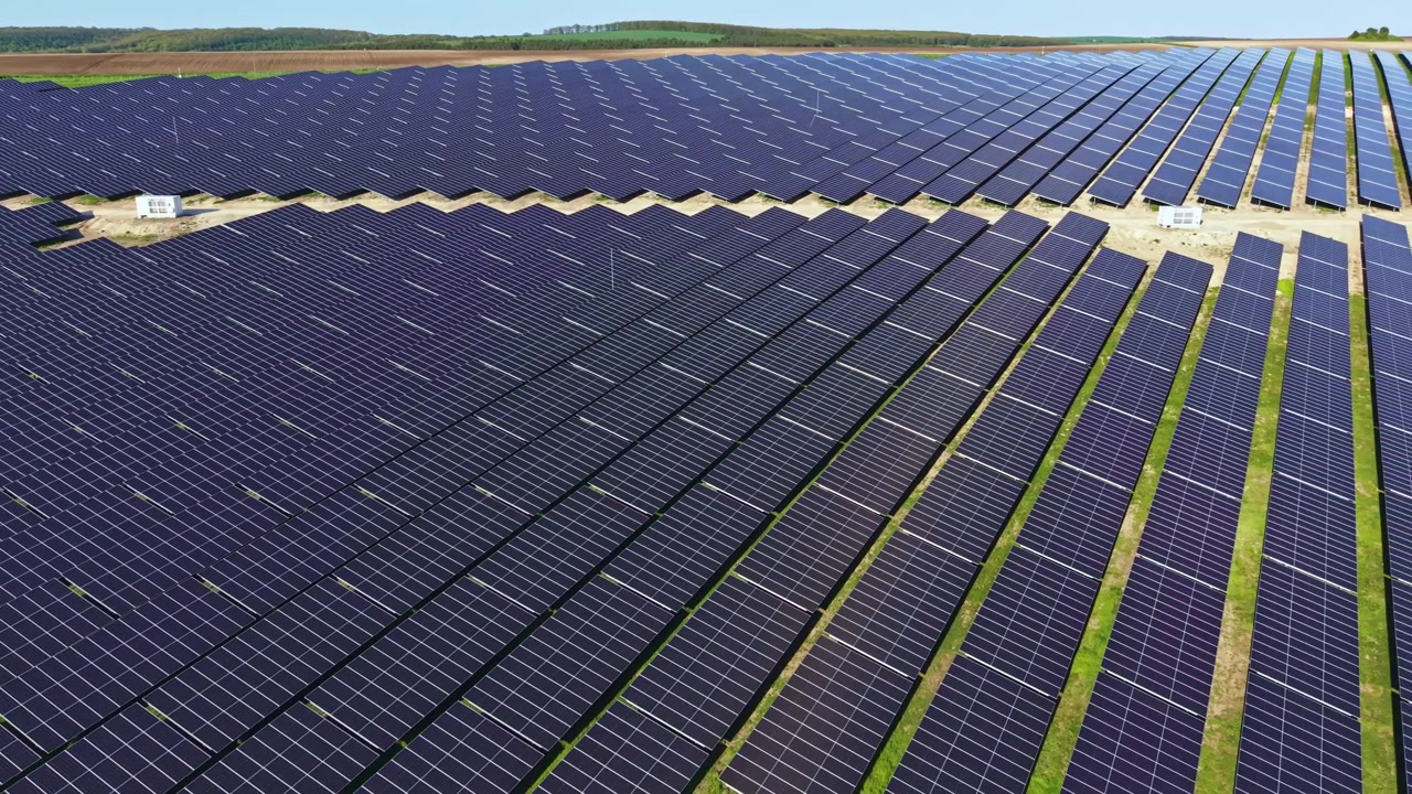 Pannelli solari coprono il terreno in un'ampia schiera, mostrando file di pannelli che raggiungono l'orizzonte sotto un cielo azzurro e limpido in questo sito di energia rinnovabile.