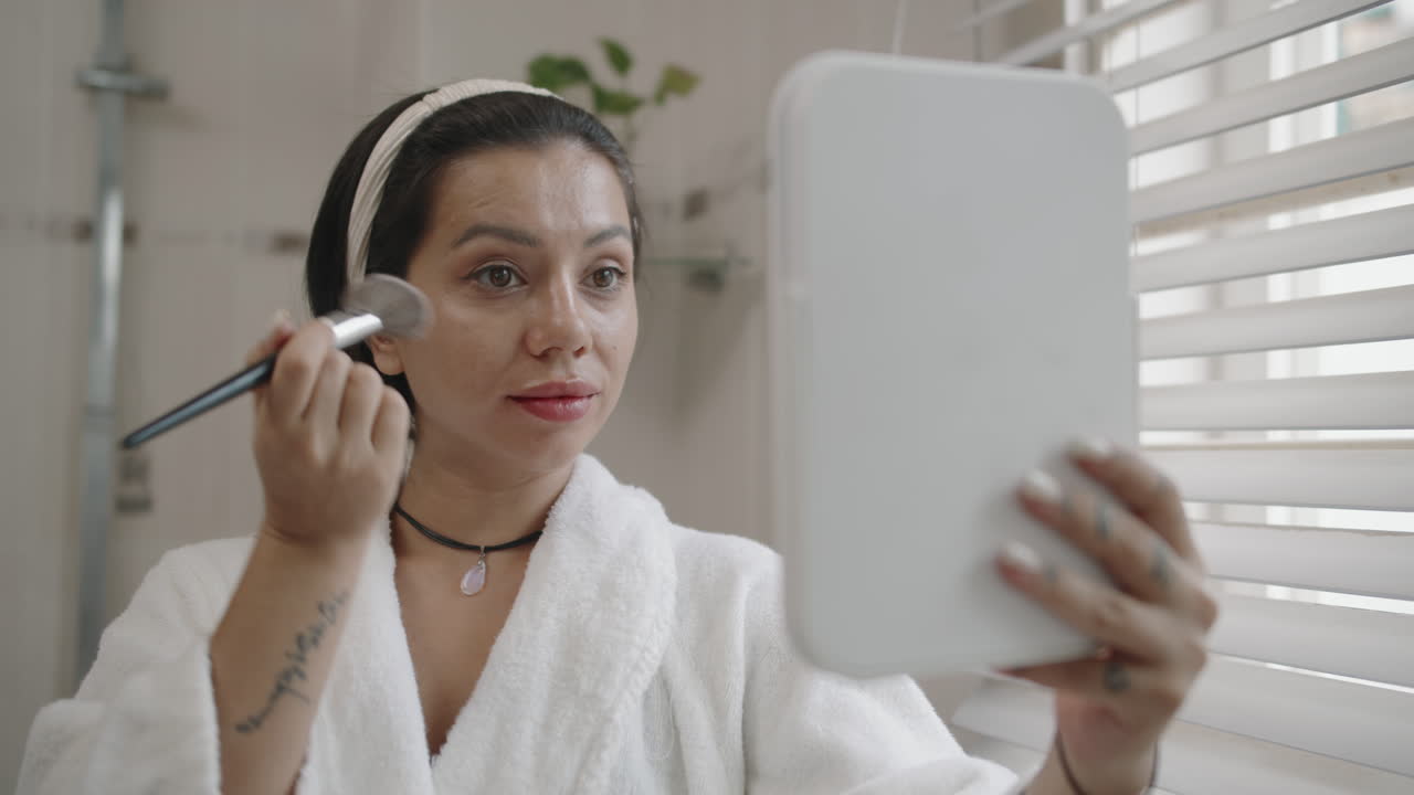 Young Woman Doing Makeup with Brush in Bathroom