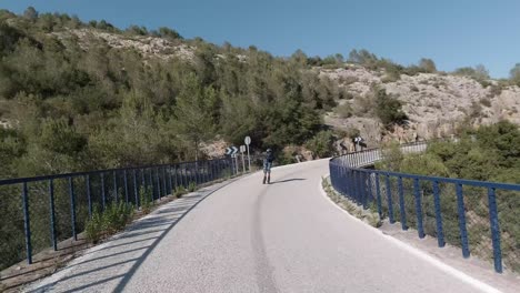 front facing follow shot of roller skater crossing a bridge in a mountain road