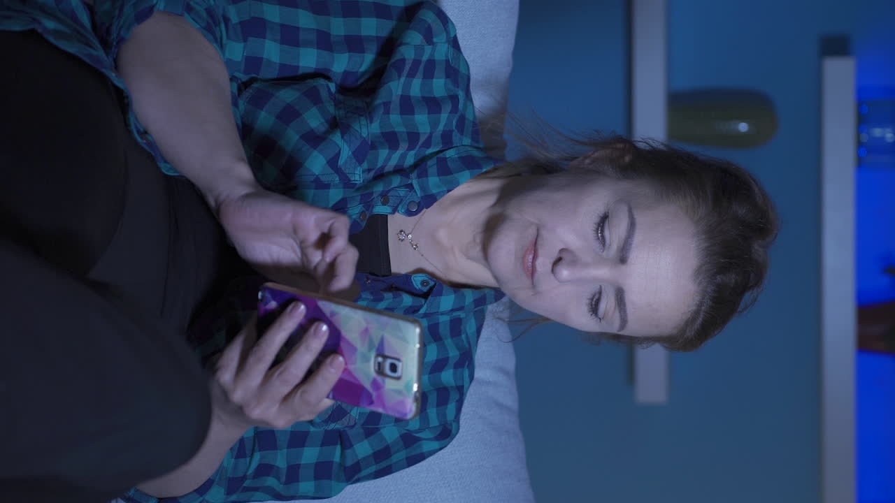 video vertical de una mujer acostada en el sofá está usando el teléfono. postura agradable y cómoda.