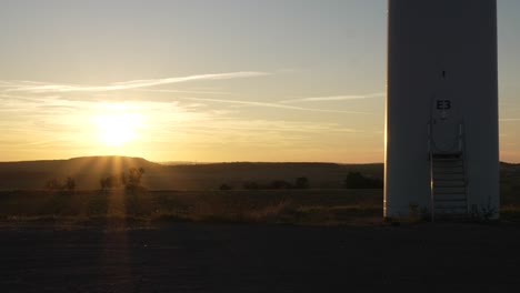 sunrise sunset at the base of wind turbine in rural landscape, beautiful sky