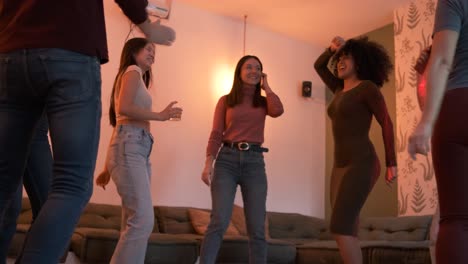excited diverse friends dancing while enjoying weekend party at home