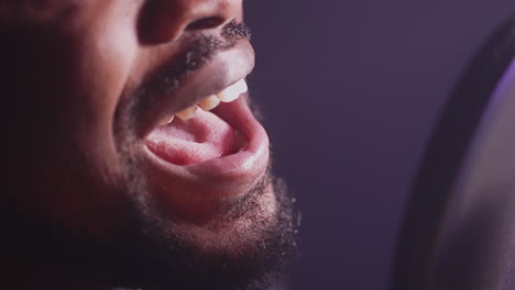 hombre cantando en un micrófono en un estudio de grabación