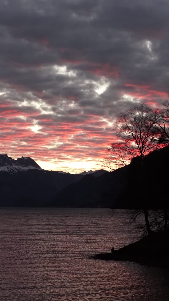Vertical view of sunset clouds above Walensee lake and alpine mountains