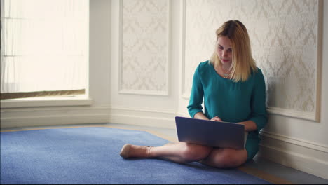 Beautiful-woman-sitting-on-floor-in-room-and-using-laptop-computer.
