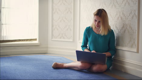 Schöne-Frau-Sitzt-Auf-Dem-Boden-Im-Zimmer-Und-Benutzt-Einen-Laptop.