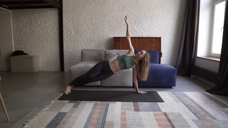 Woman-performing-bodyweight-fitness-training-at-her-apartment-doing-side-plank