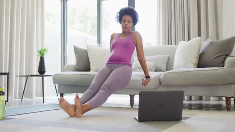 Happy-african-american-wearing-sportswear,-exercising,-using-laptop