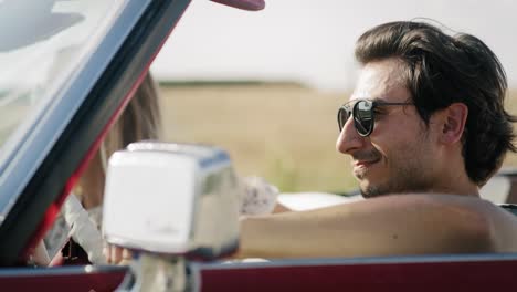 Side-view-of-couple-driving-in-a-red-cabriolet