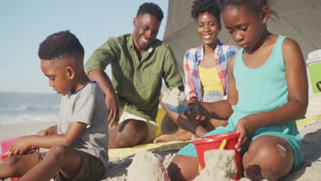african american brother and sister playing with sand on the beach
