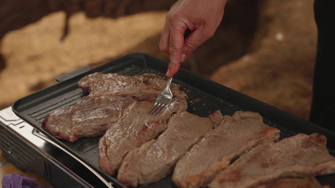 Filetes de carne asándose en una plancha eléctrica portátil en un campamento del desierto del Sahara, Marruecos