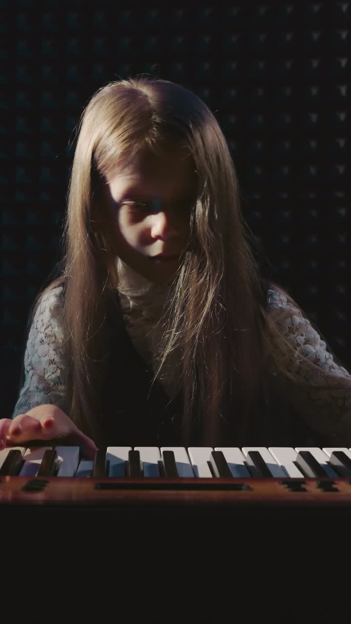 Tiny artist plays musical device in recording studio. Girl pianist brings melodies to life on synthesizer in musical academy. Flourishing of talents