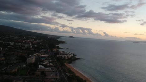 AERIAL-DRONE-FOOTAGE-OF-THE-SURF-OFF-THE-COAST-IN-KIHEI-MAUI-HAWAII-WITH-MOLIKINI-ISLAND-AND-KAHO'OLAWE-IN-THE-BACKGROUND