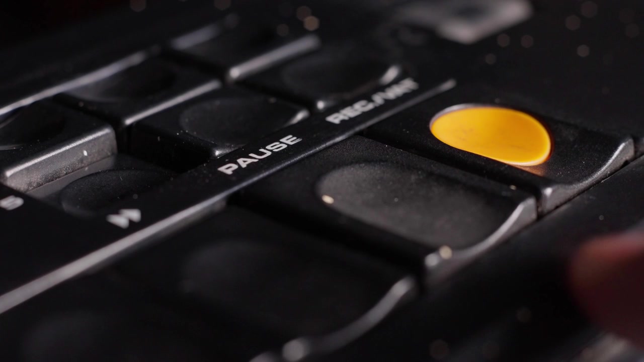 Finger presses control button down to pause buttons on vintage analog audio equipment, raise to release