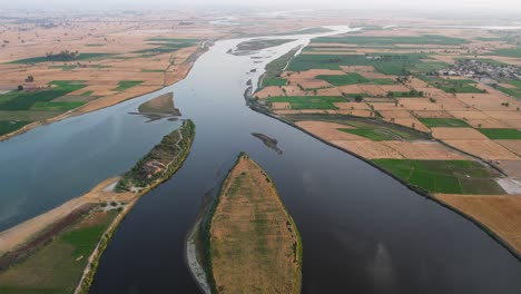 sutlej river dividing around cultivated islands amid patchwork farmlands. punjab, pakistan
