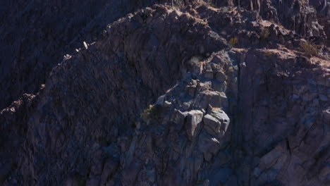 Epic-scene-of-the-Flag-of-the-United-States-of-America-sits-proudly-and-tall-above-a-rocky-mountain-in-Indio-California-on-a-windy-day