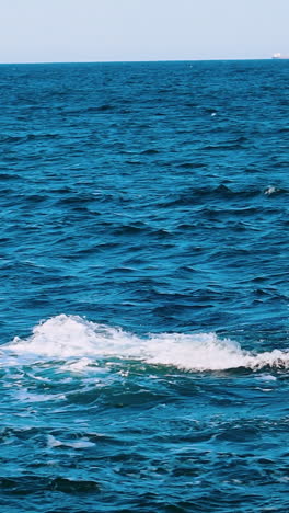 amazing water background. waves swaying on the sea water. beautiful blue water waves with white foam crashing on the dock. slow motion. vertical video