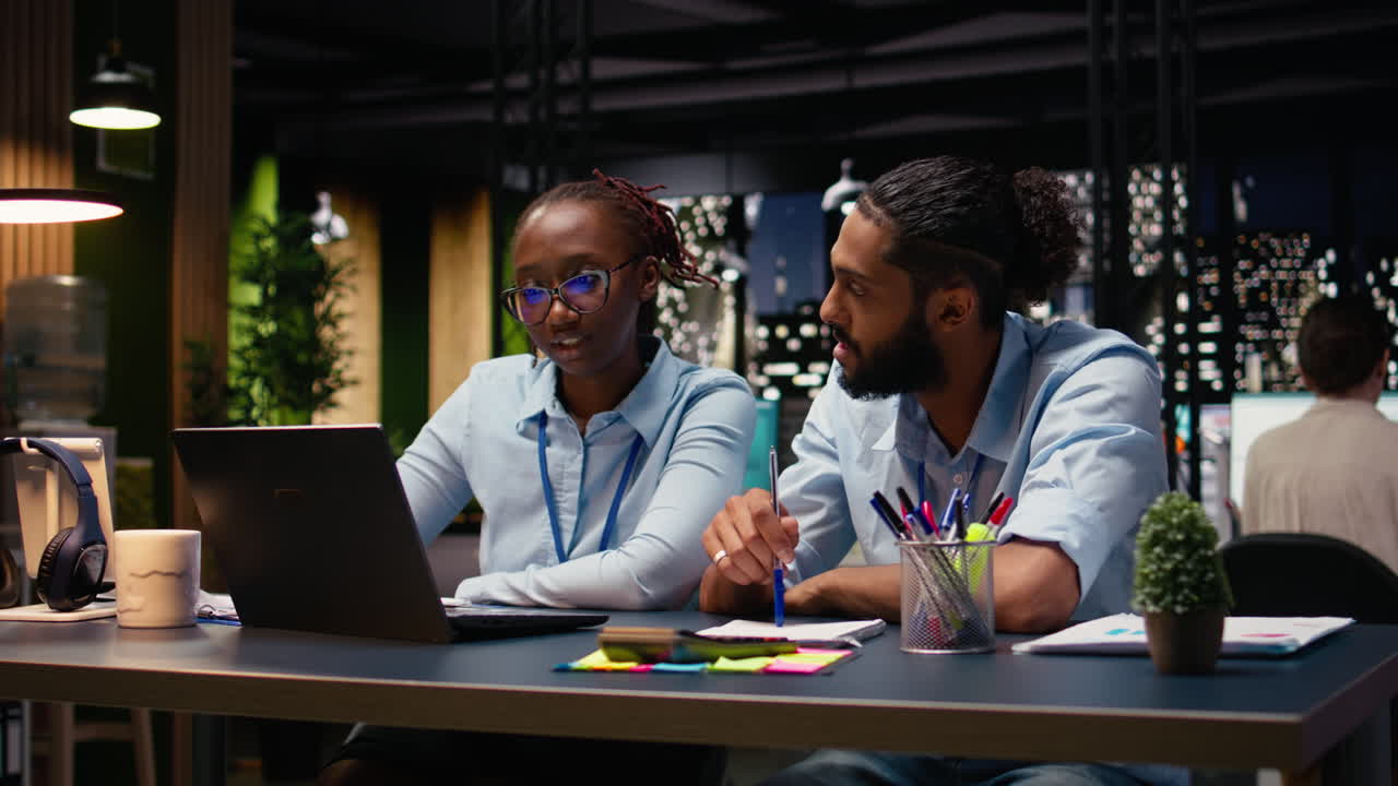 Smiling business associates in office evaluating staff performance with laptop