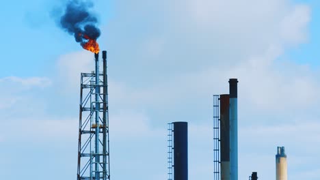 Top-of-an-industrial-refinery-emitting-polluting-black-smog-into-a-clear-blue-sky-in-beautiful-Curacao