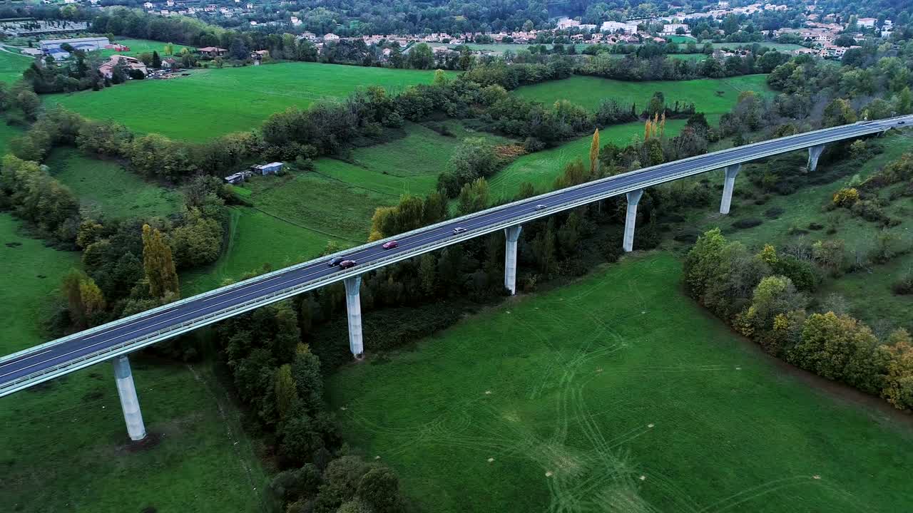 프랑스의 한 다리에 있는 고속도로 도로 위에서 드론을 이용한 공중 전망 - 도로 주변에는 잔디과 나무만 있고, 차와 트럭이 빛 아래 도로를 달리고 있다.