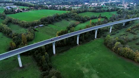 aerial view with a drone over a highway road on a bridge in france. only grass fields and trees around the roads. cars and trucks driving on the roads under the sun.