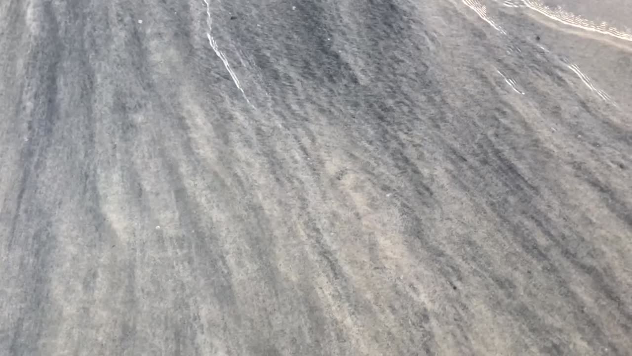 슬로우 모션으로 모래 해안에 검은 광물 바다 퇴적물의 상위 뷰