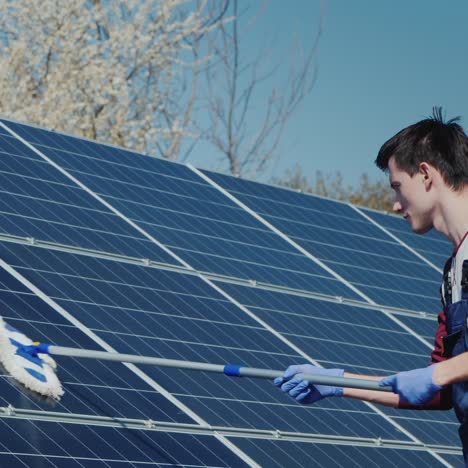 Vista-Lateral-Del-Hombre-Lavando-Paneles-Solares-En-La-Planta-De-Energía-Doméstica