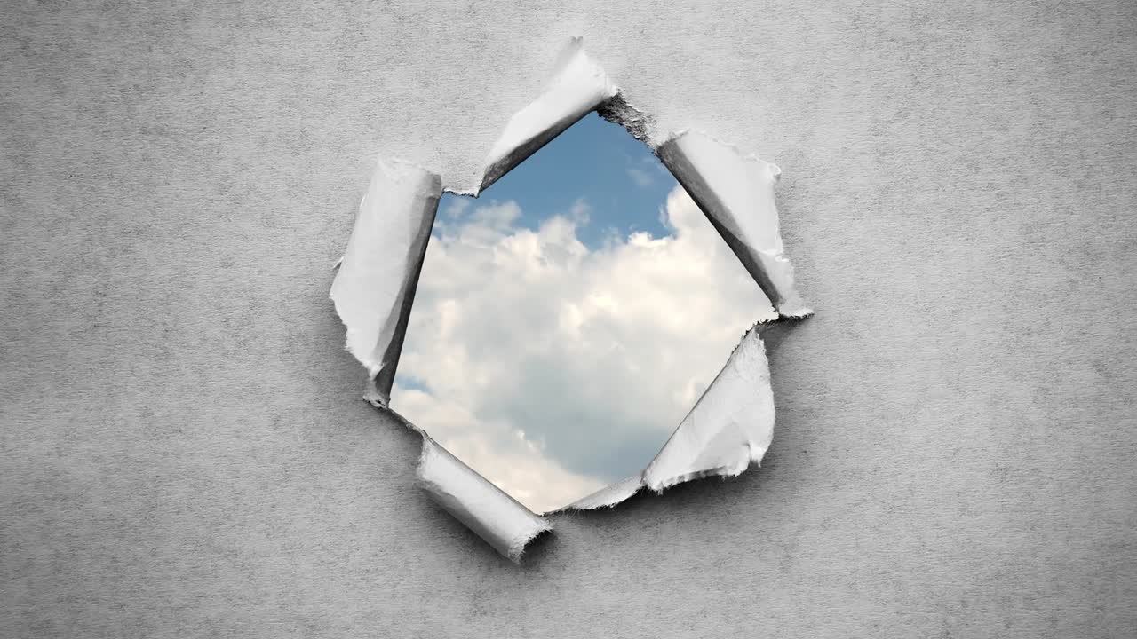 un video creativo de 4k de nubes en movimiento rápido en el cielo azul que son visibles a través de un agujero circular con bordes rasgados en viejo papel vintage retro grunge.