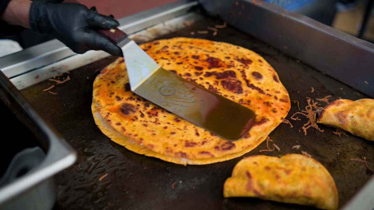 Kaupallisen keittiön kuvamateriaalia, jossa birria-pizzaa paistetaan öljyllä suolaisen birria-pizzan valmistuksen aikana tasoparilalla.