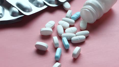 medicine pills and blister packs on pink surface