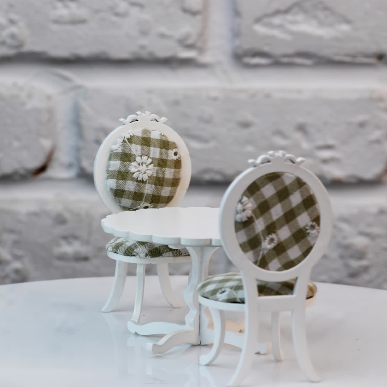 Toy furniture set containing a table and two chairs. White one-leg table and chairs with colored casing on the rotating stand. Close up