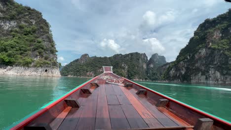 passenger pov from wooden longboat cruising in the lake in khao sok national park, thailand