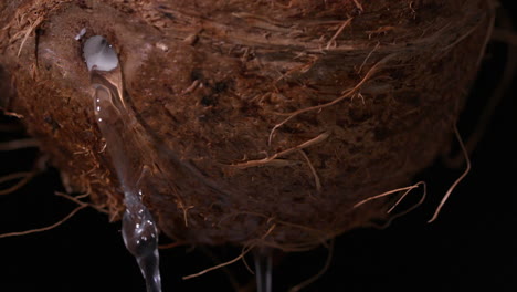 agua que se filtra del coco sobre un fondo negro