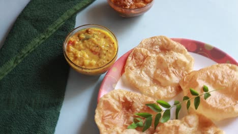 rotación chole bhature o curry de garbanzos y puri frito servido en vajilla de terracota sobre fondo azul