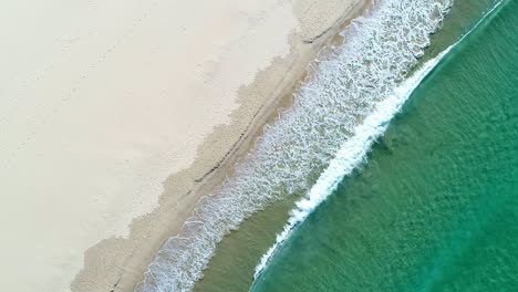 Welle-Stürzt-Bei-Sonnenaufgang-An-Einen-Weißen-Sandstrand