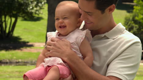 Man-holding-his-baby-daughter-in-the-park