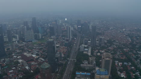 Aerial-wide-slow-shot-of-multi-lane-highway-passing-through-busy-modern-city-center-with-skyscrapers-and-dense-residential-neighborhoods-in-Jakarta