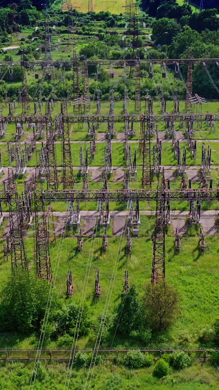 High voltage steel pylons in green field. View from above the power transmission lines. Electric tower line among nature. Aerial view. Vertical video