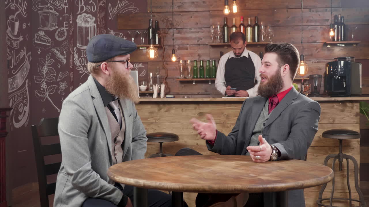 Two men in suits having a conversation at a bar