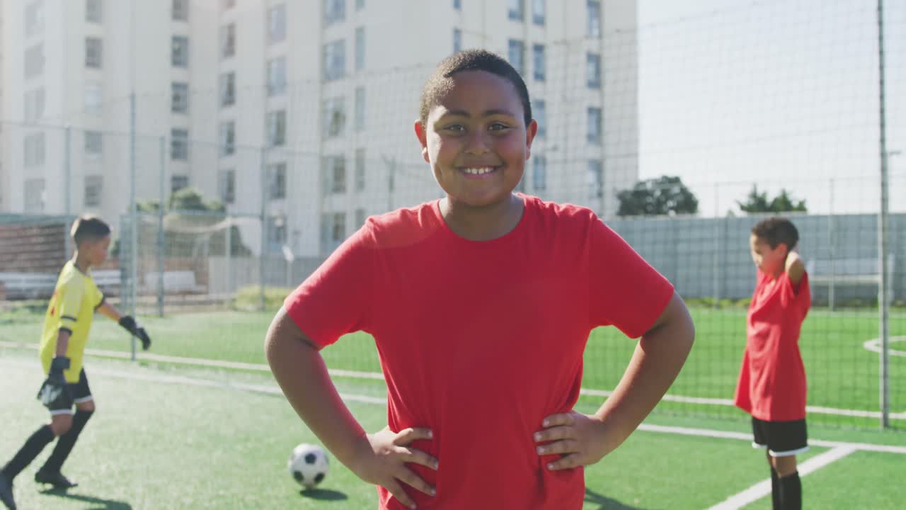niño de fútbol afroamericano en rojo sonriendo y mirando a la cámara