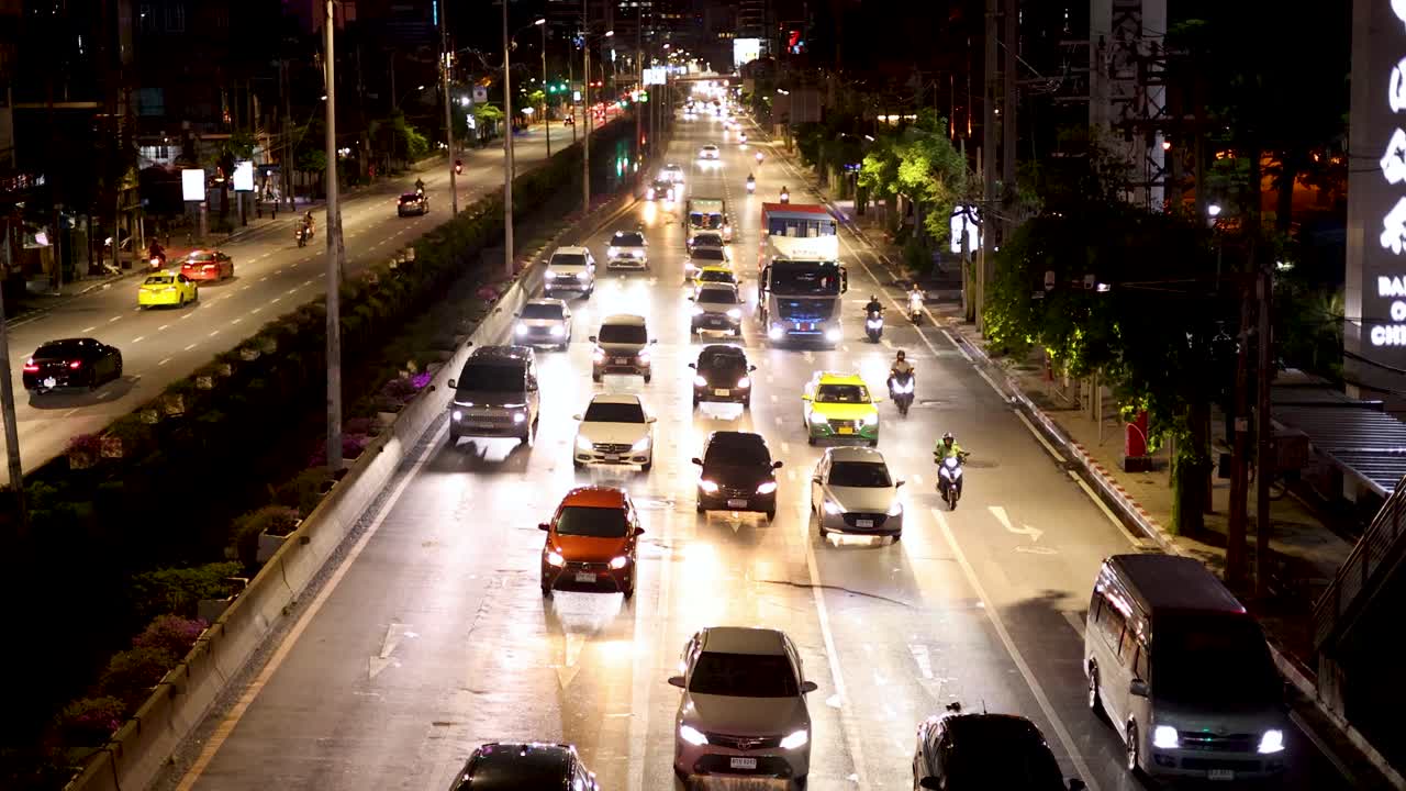 Overhead view of busy nighttime traffic, illuminated by streetlights, with steady camera perspective