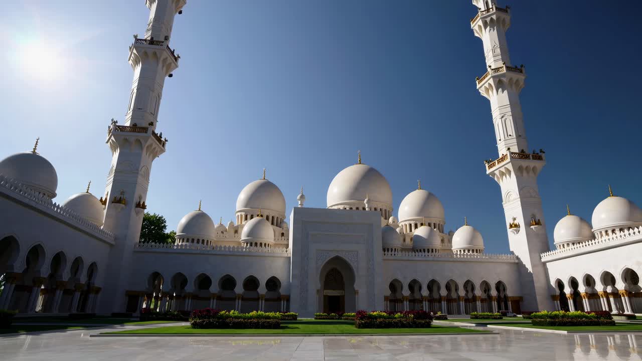 Lav engel videooptagelse af en storslået moské med hvide kupler og minareter under en klar, blå himmel