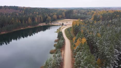 Stimmungsvolle-Eleganz:-Eine-Malerische-Straße-Am-See-Und-Wald,-Die-Verschneite-Ruhe-Mit-Herbstlichen-Farben-Verbindet