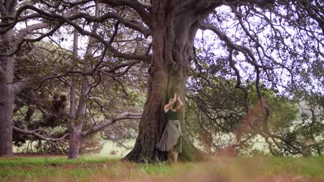 a woman in black dress cheerfully leaning on a tree to make a pose