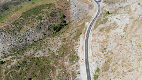 drone filmado inclinándose y moviéndose hacia adelante, filmando algunos coches conduciendo en una carretera en las colinas de andalucía, españa