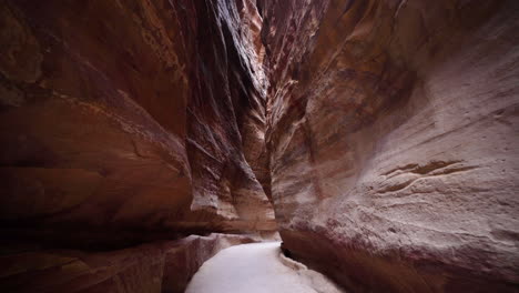 narrow and depp passage of al siq canyon with red rock walls from both sides in ancient city of petra