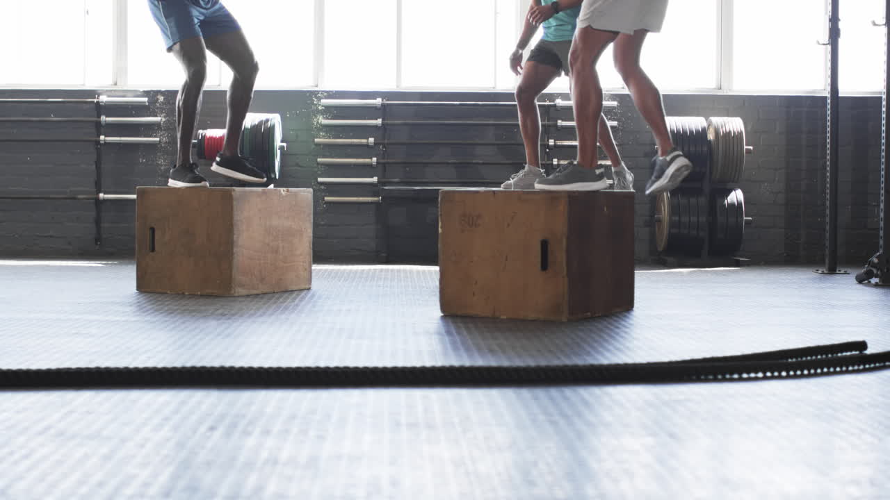 Exercising in gym, men doing box jumps for fitness training workout