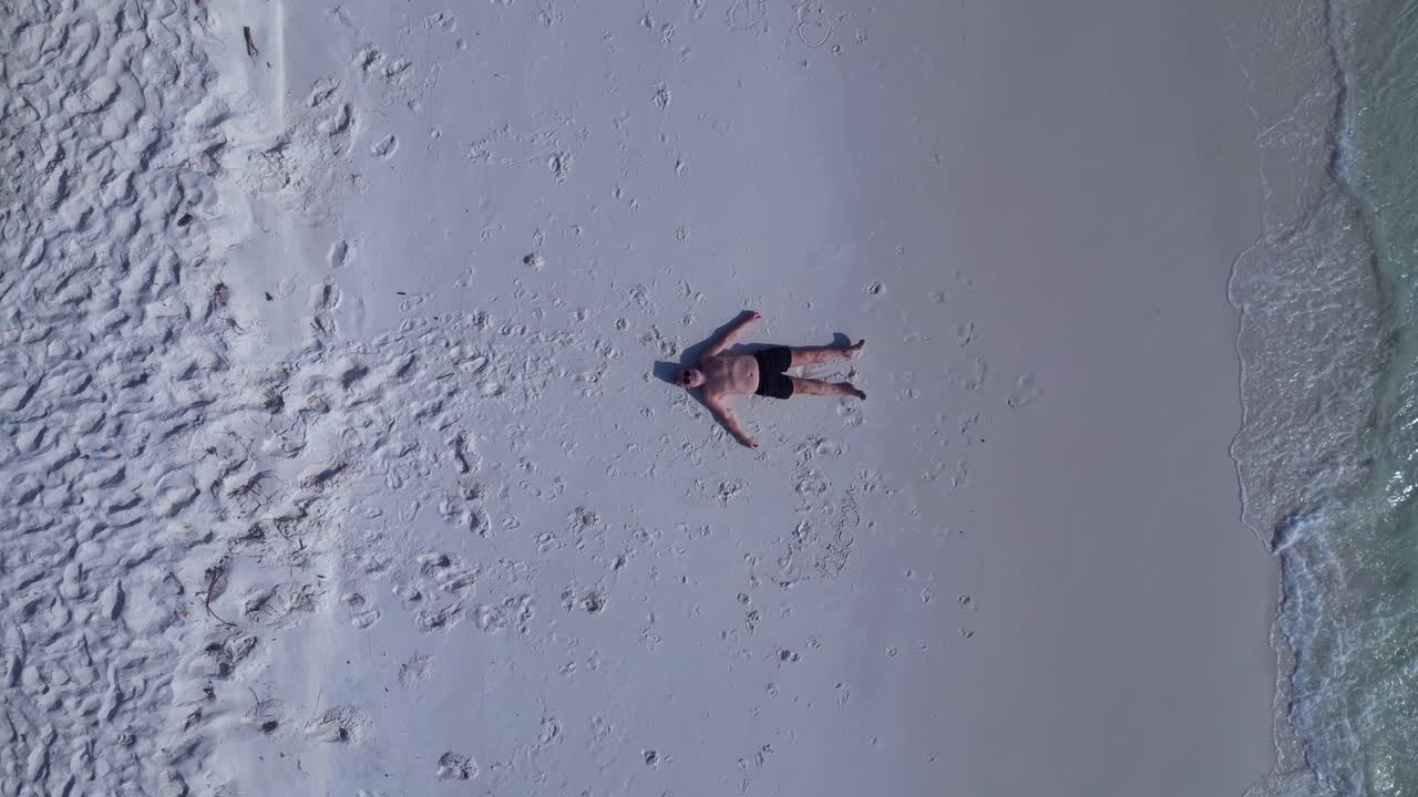 Tourist lying on a beautiful tropical beach, enjoying the sun and the sound of the waves. Breathtaking aerial view flight speed ramp hyper motion time lapse